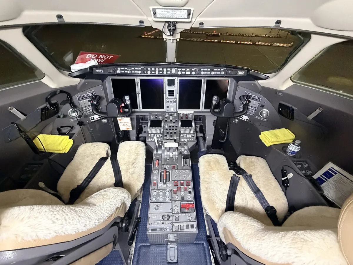 Bombardier Challenger 300 full cockpit flight deck with sheepskin seat covers, throttle quadrant, and instrument panels after detailing at PWK