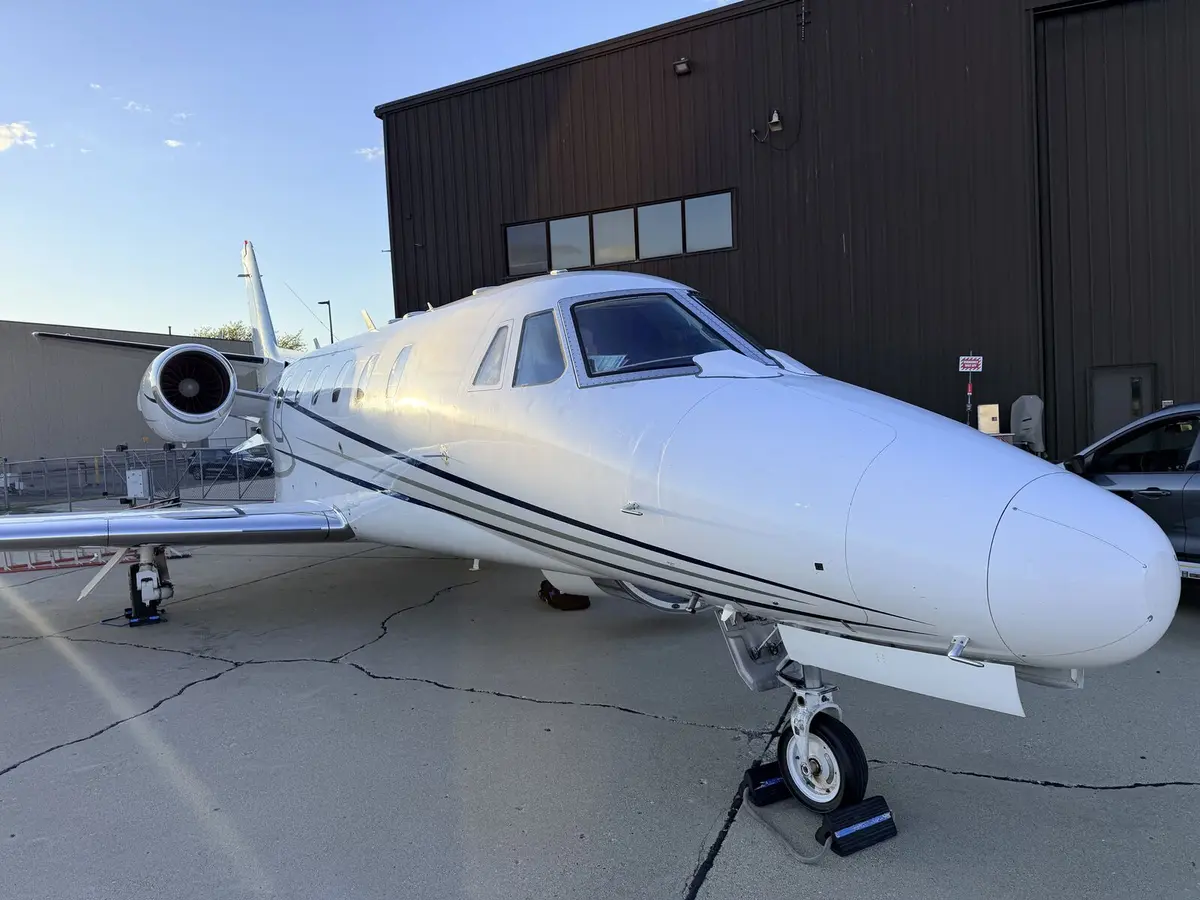 Cessna Citation Excel nose and fuselage quarter view parked on ramp near hangar during golden hour after exterior detailing