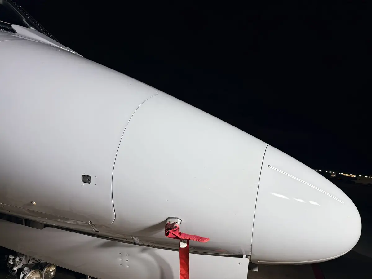 Cessna Citation X nose radome and pitot tube with red remove-before-flight flag after exterior detail at night