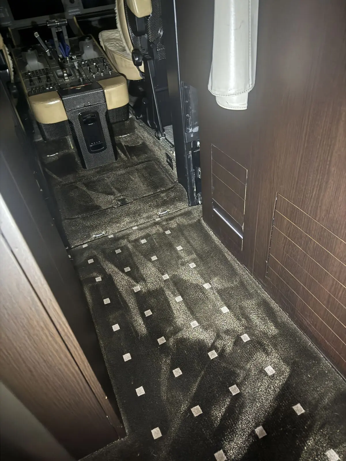 Private jet cabin patterned carpet aisle with diamond pattern and cockpit threshold visible after carpet extraction