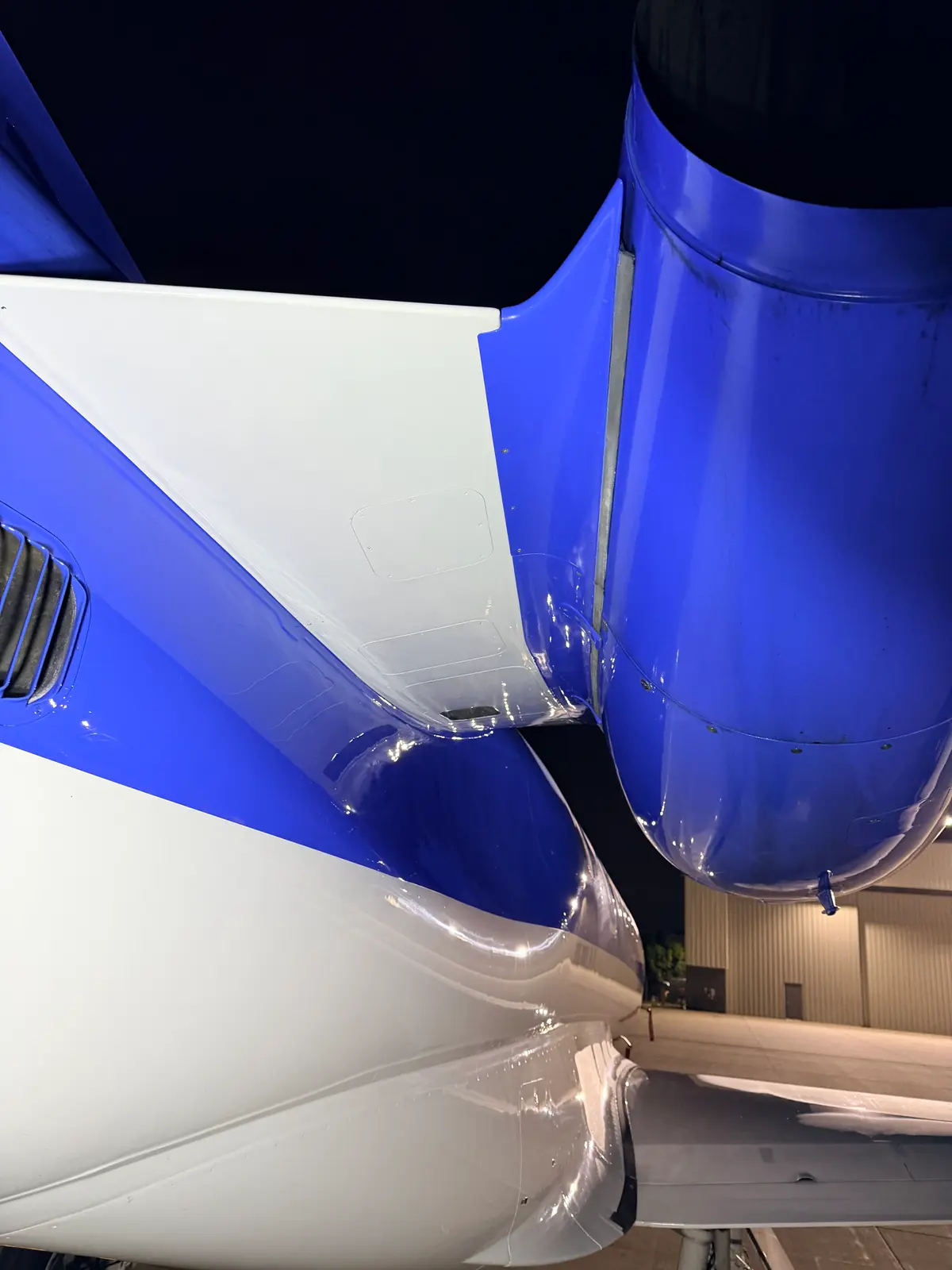 Embraer Phenom 300 engine fan face with polished spinner and fan blades framed by a blue cowl at night